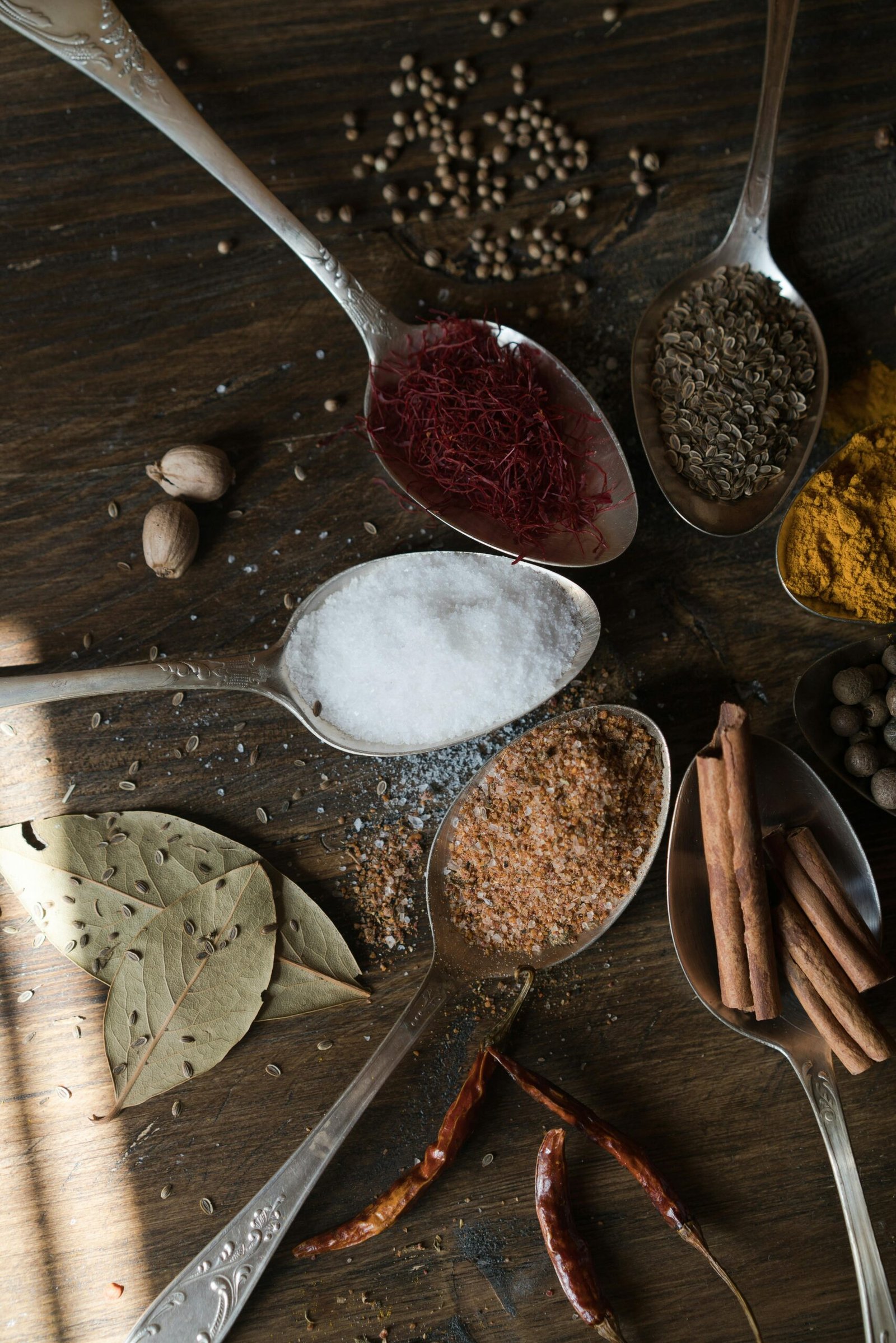 Indian spices for weight loss including turmeric cinnamon jeera saffron and red chillies on silver spoons