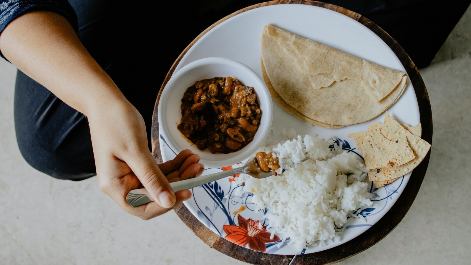 Person eating Indian vegetarian meal of rajma rice and roti showing correct plate portions