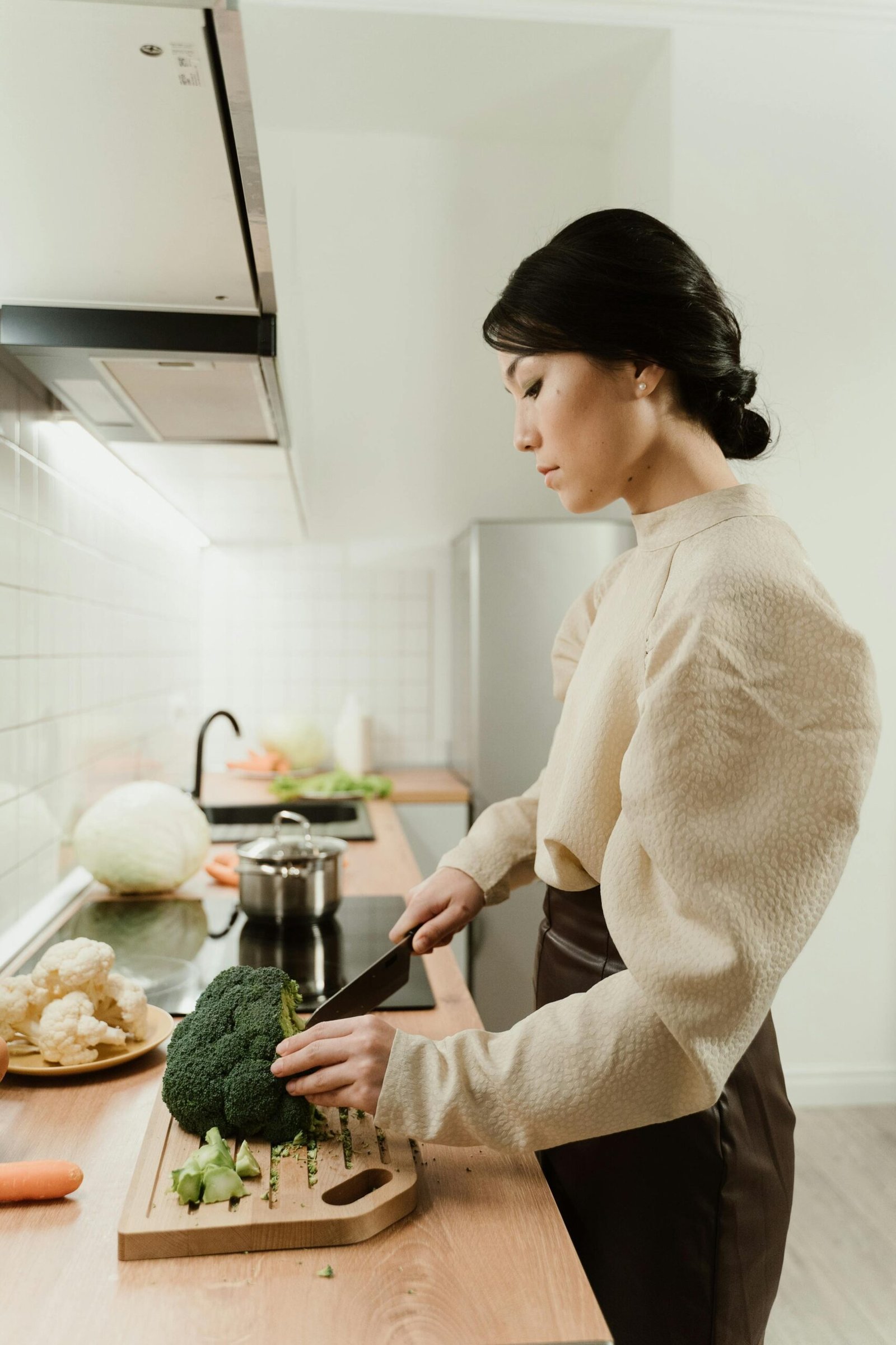 Woman chopping broccoli and vegetables in the kitchen staying committed to a vegetarian diet