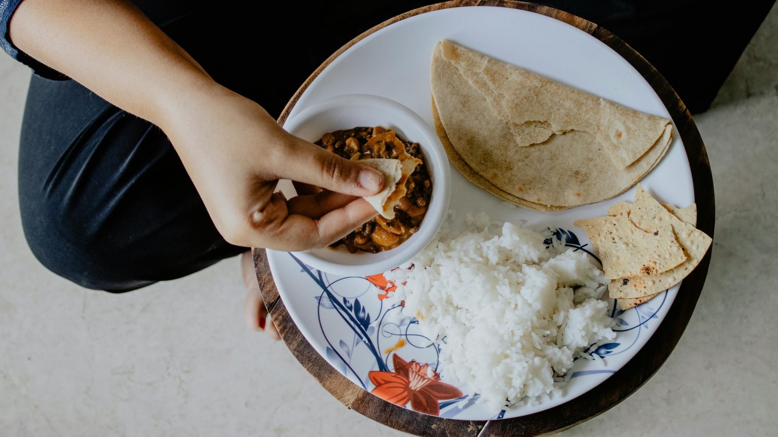 Person eating a vegetarian meal of dal, roti and rice - a complete plant-based plate