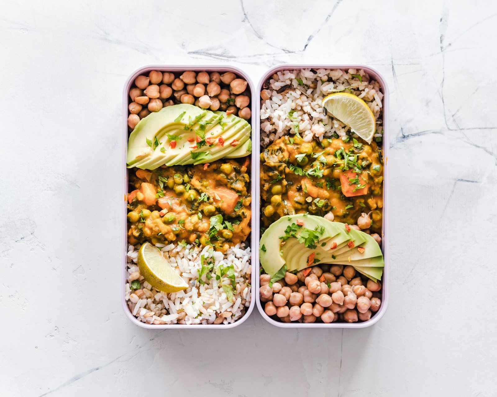 Two meal prep containers with dal curry chickpeas and brown rice batch cooked for the week